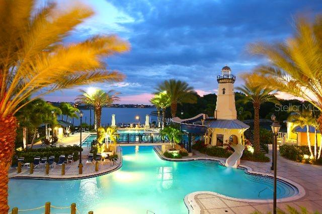 pool at dusk with a water view, a patio, and a water slide