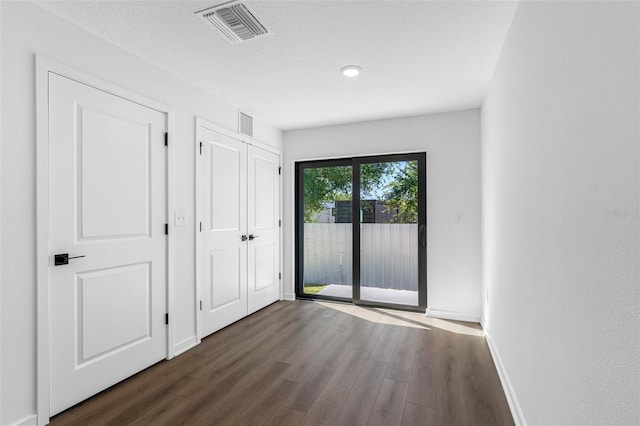 unfurnished bedroom featuring dark wood-type flooring, a textured ceiling, and access to outside