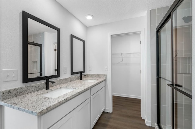 bathroom with vanity, hardwood / wood-style floors, a shower with door, and a textured ceiling