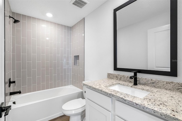 full bathroom with vanity, hardwood / wood-style flooring, toilet, and tiled shower / bath