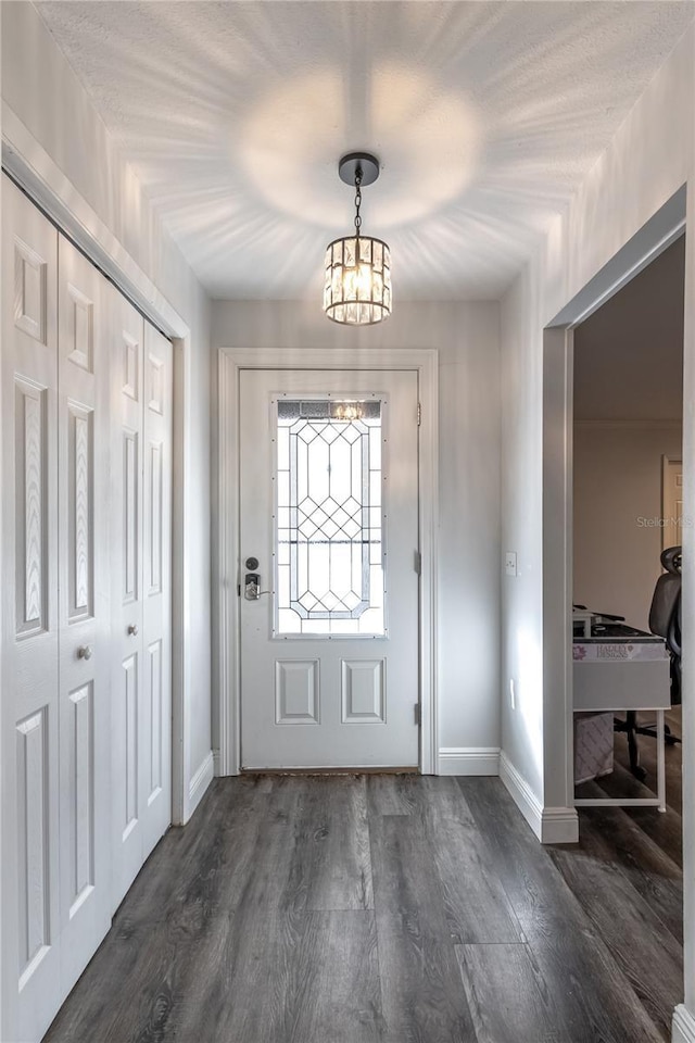 entrance foyer with an inviting chandelier and dark hardwood / wood-style flooring