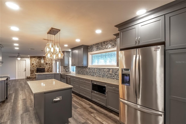 kitchen with tasteful backsplash, decorative light fixtures, a center island, appliances with stainless steel finishes, and gray cabinets