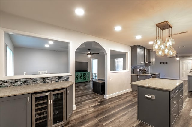 kitchen featuring gray cabinets, dark hardwood / wood-style floors, pendant lighting, beverage cooler, and a center island