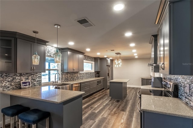 kitchen featuring light stone counters, dark hardwood / wood-style flooring, decorative light fixtures, and a center island