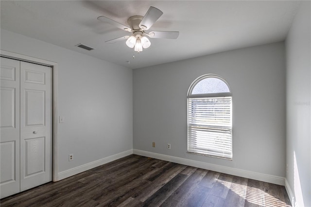 empty room featuring dark wood-type flooring and ceiling fan