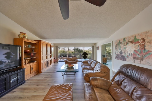 living room featuring vaulted ceiling, a textured ceiling, and light hardwood / wood-style floors