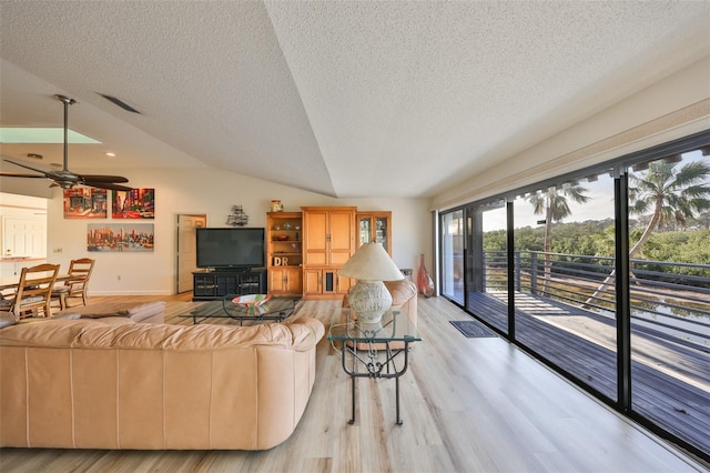 living room featuring ceiling fan, light hardwood / wood-style flooring, a textured ceiling, and vaulted ceiling