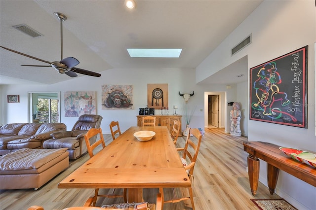 dining space with light hardwood / wood-style flooring, lofted ceiling with skylight, and ceiling fan