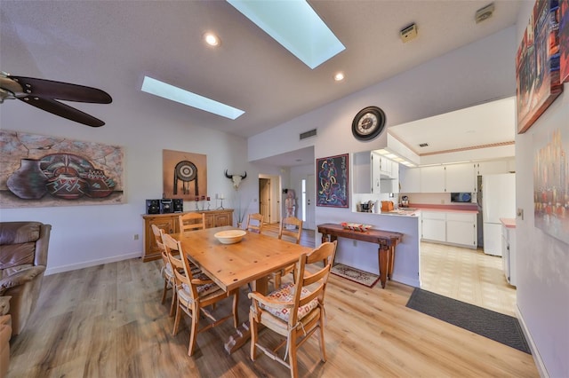 dining room with lofted ceiling with skylight, ceiling fan, and light hardwood / wood-style floors