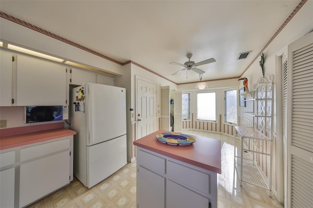 kitchen with white cabinetry, ornamental molding, ceiling fan, and white fridge