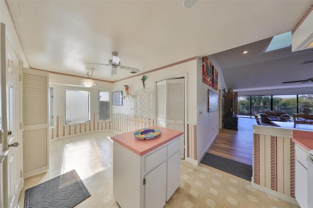 kitchen with crown molding, dishwasher, ceiling fan, white cabinetry, and a kitchen island