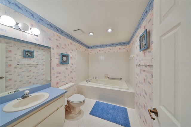 bathroom with tile patterned flooring, vanity, a relaxing tiled tub, and toilet