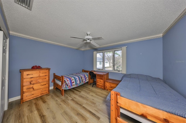 bedroom with ceiling fan, crown molding, light hardwood / wood-style floors, and a textured ceiling