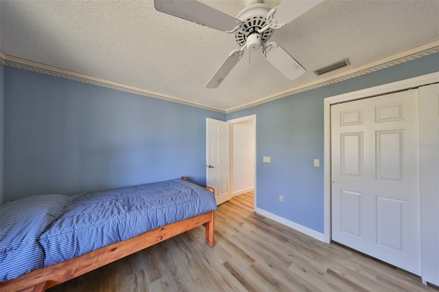 bedroom featuring ceiling fan, ornamental molding, light hardwood / wood-style floors, and a textured ceiling