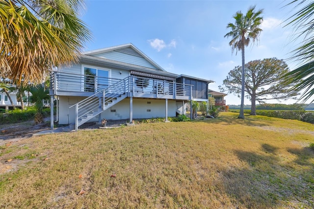 rear view of property featuring a lawn, a sunroom, and a deck