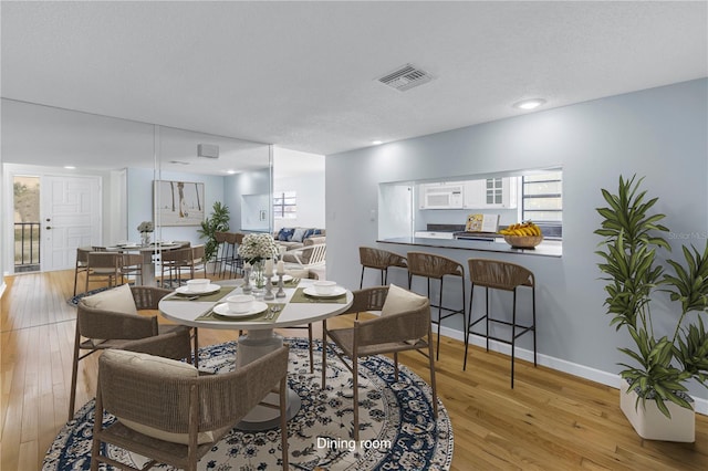 dining space featuring a textured ceiling and light wood-type flooring