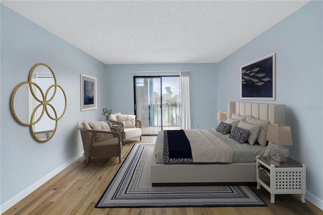 bedroom featuring access to exterior, a textured ceiling, and light wood-type flooring