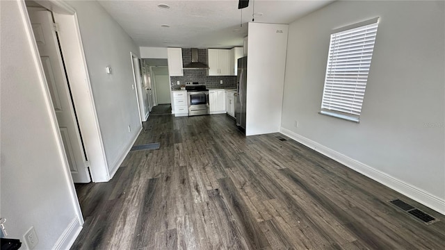 kitchen featuring wall chimney range hood, appliances with stainless steel finishes, backsplash, white cabinets, and dark hardwood / wood-style flooring