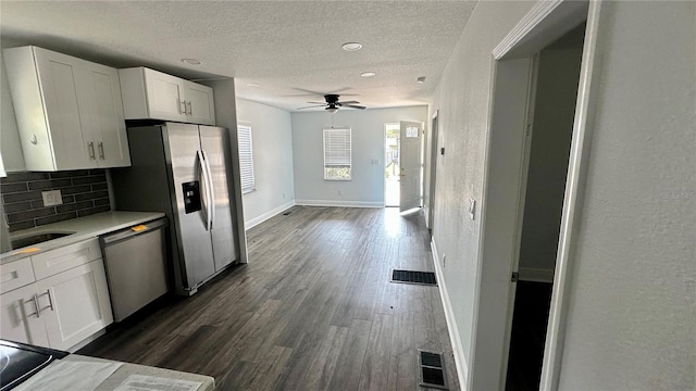 kitchen featuring stainless steel appliances, white cabinets, a textured ceiling, dark hardwood / wood-style flooring, and decorative backsplash