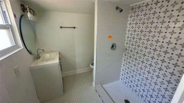 bathroom with vanity, tiled shower, tile patterned floors, and toilet