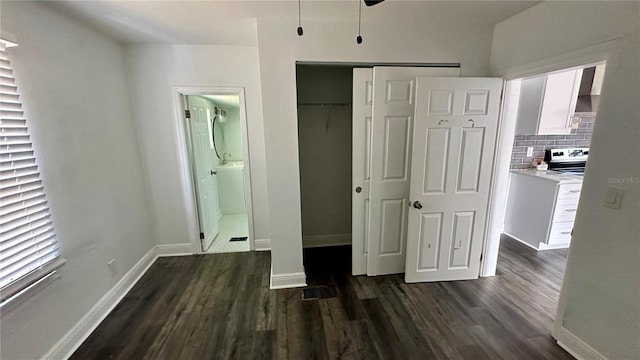 unfurnished bedroom featuring ensuite bathroom, dark wood-type flooring, and a closet