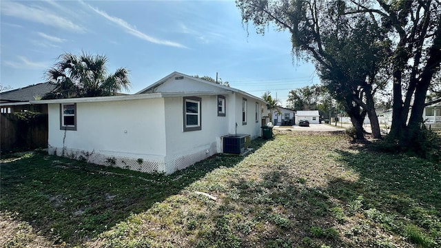 view of property exterior featuring central AC and a lawn