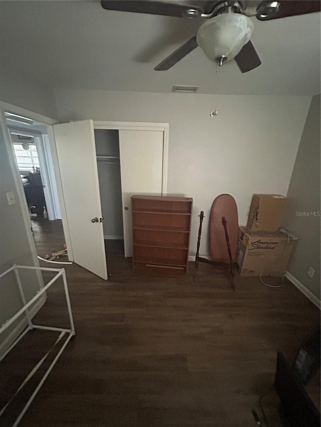 unfurnished bedroom featuring dark wood-type flooring, a closet, and ceiling fan