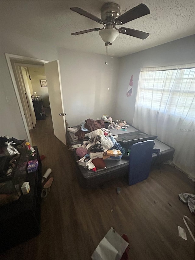 bedroom featuring dark hardwood / wood-style flooring, ceiling fan, and a textured ceiling