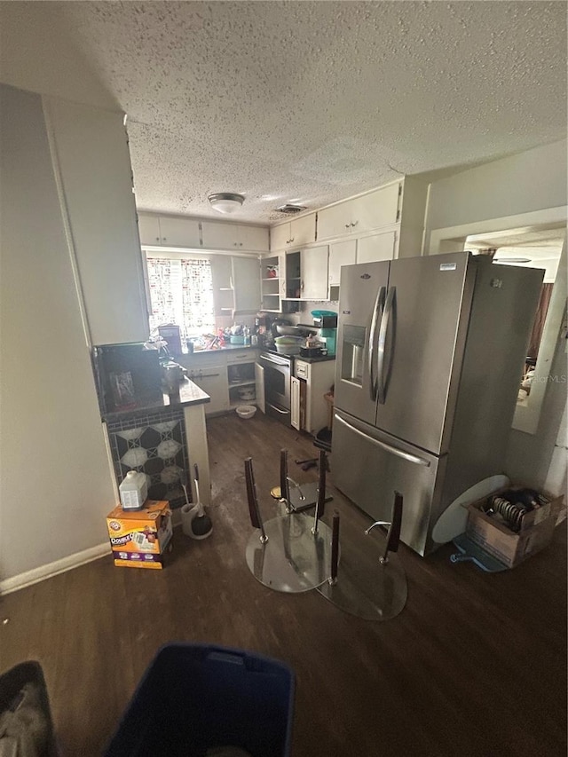 kitchen with appliances with stainless steel finishes, dark wood-type flooring, white cabinets, and a textured ceiling