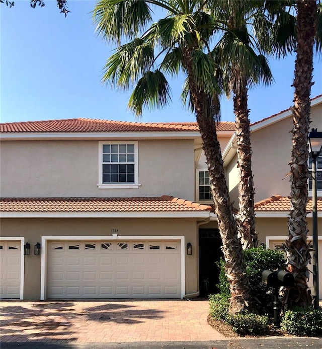 view of front facade featuring a garage, decorative driveway, and stucco siding