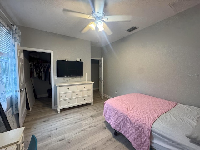 bedroom with visible vents, baseboards, a closet, light wood-type flooring, and a walk in closet