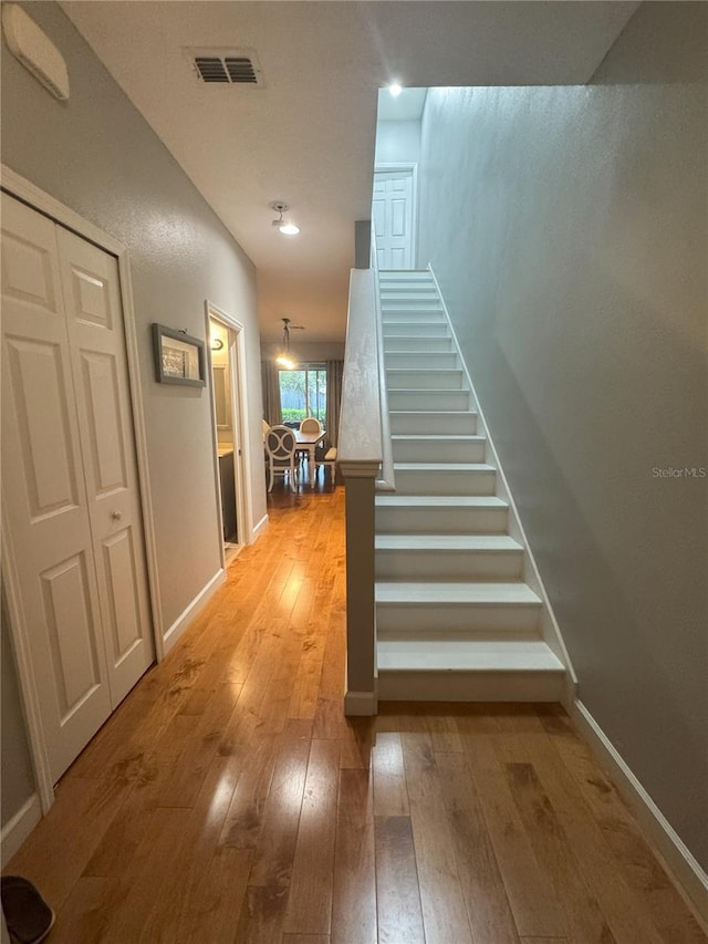 stairway featuring visible vents, baseboards, and wood finished floors