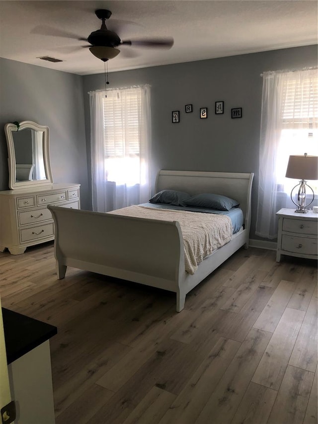 bedroom with light wood-type flooring, ceiling fan, and visible vents