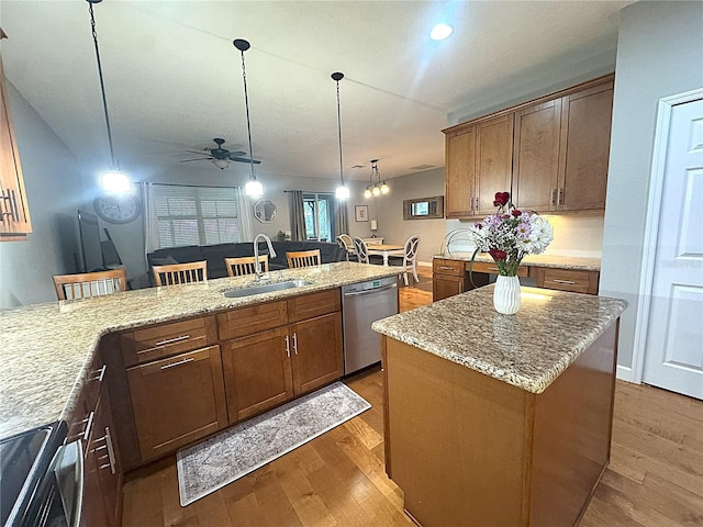 kitchen with stainless steel appliances, a sink, a kitchen island, a kitchen breakfast bar, and hanging light fixtures