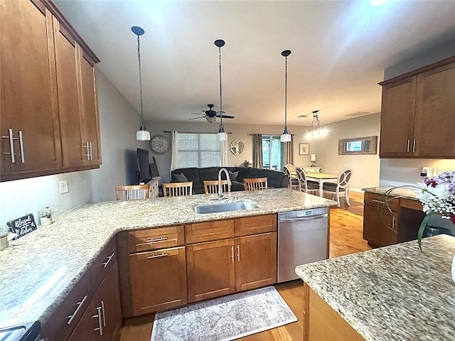 kitchen with light stone counters, open floor plan, stainless steel dishwasher, pendant lighting, and a sink