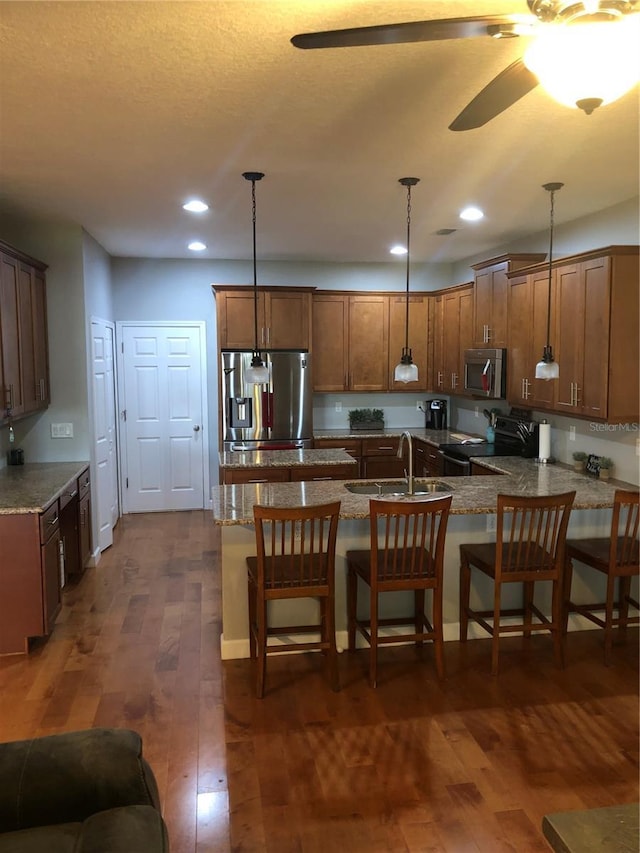 kitchen featuring a breakfast bar, a peninsula, appliances with stainless steel finishes, and pendant lighting