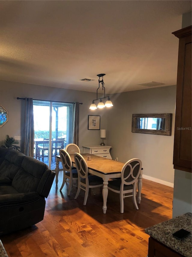 dining room featuring baseboards, visible vents, and wood finished floors