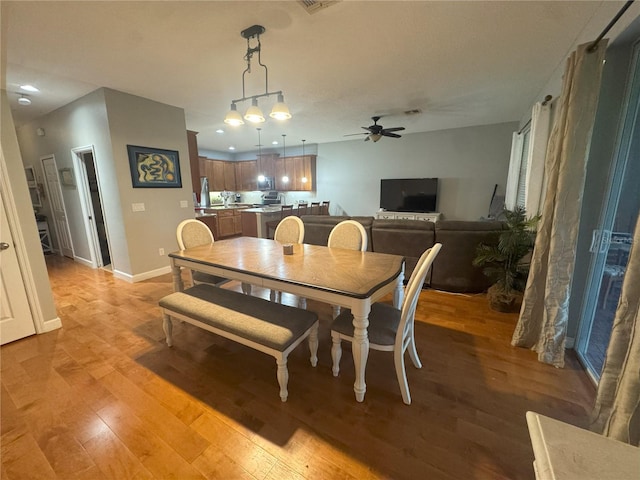 dining room featuring light wood-type flooring, a ceiling fan, and baseboards