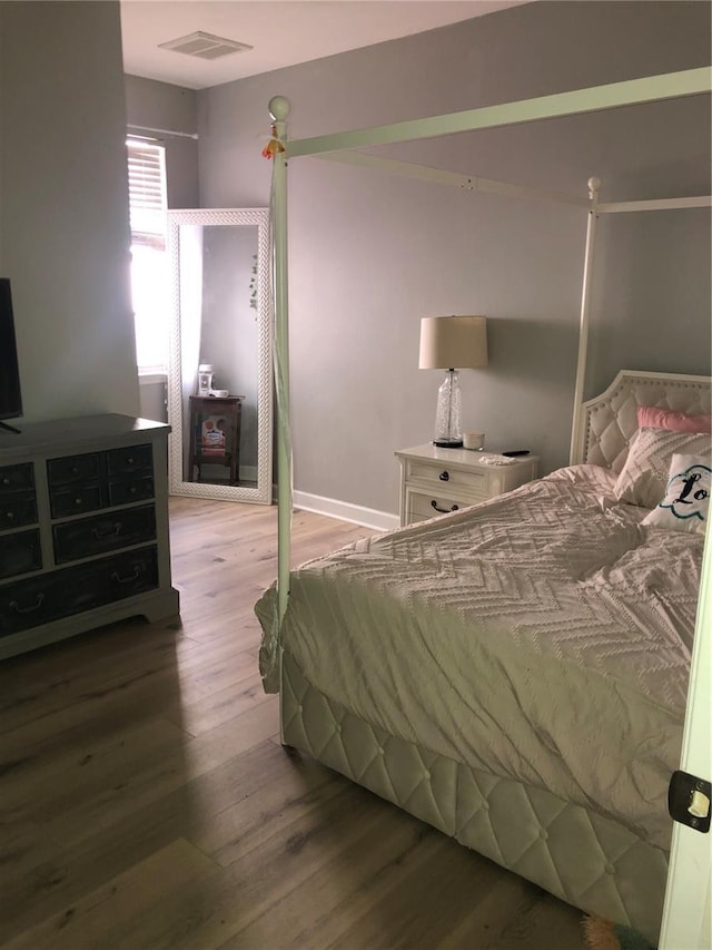 bedroom with wood finished floors, visible vents, and baseboards