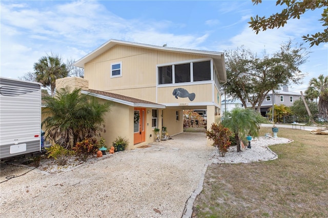 view of front facade with dirt driveway and a carport