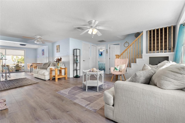 living room with hardwood / wood-style floors, a textured ceiling, and ceiling fan