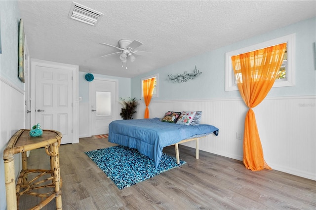 bedroom featuring hardwood / wood-style floors, a textured ceiling, and ceiling fan