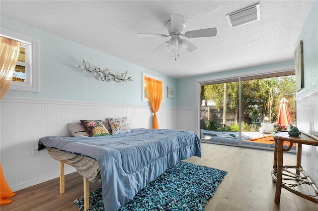 bedroom with hardwood / wood-style floors, ceiling fan, a textured ceiling, and access to exterior