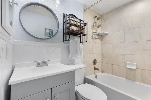 bathroom featuring a wainscoted wall, toilet, vanity, and washtub / shower combination