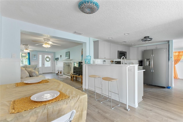 kitchen with a breakfast bar area, stainless steel appliances, a peninsula, open floor plan, and light countertops