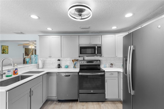 kitchen featuring light wood-style flooring, stainless steel appliances, a sink, visible vents, and light countertops