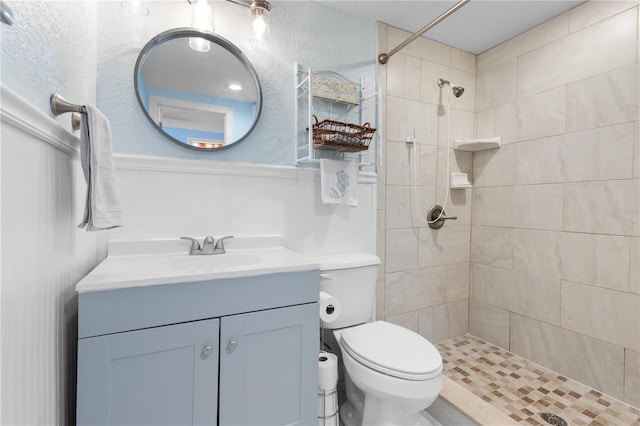 bathroom with tiled shower, vanity, and toilet