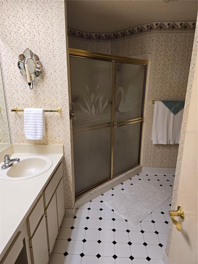 bathroom with vanity, a textured ceiling, and walk in shower