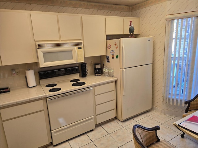 kitchen featuring tile counters, white cabinets, white appliances, and light tile patterned floors