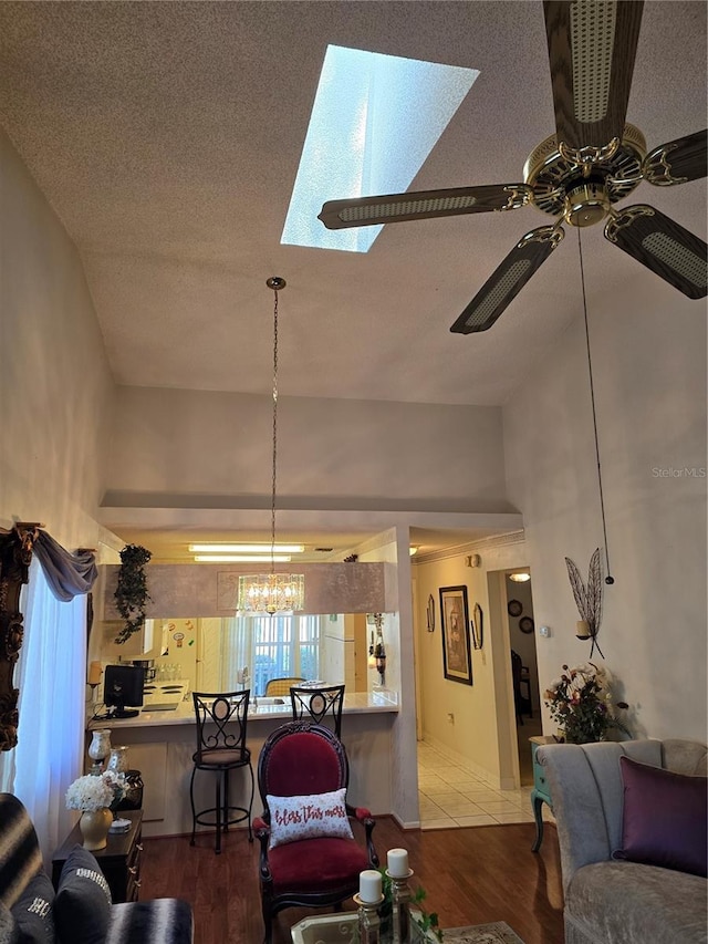 living room featuring ceiling fan with notable chandelier, a textured ceiling, and light wood-type flooring